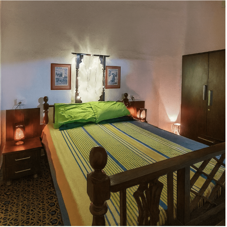 Nana's Room bed view — queen bed with white linen, heritage tiled floor, warm natural light