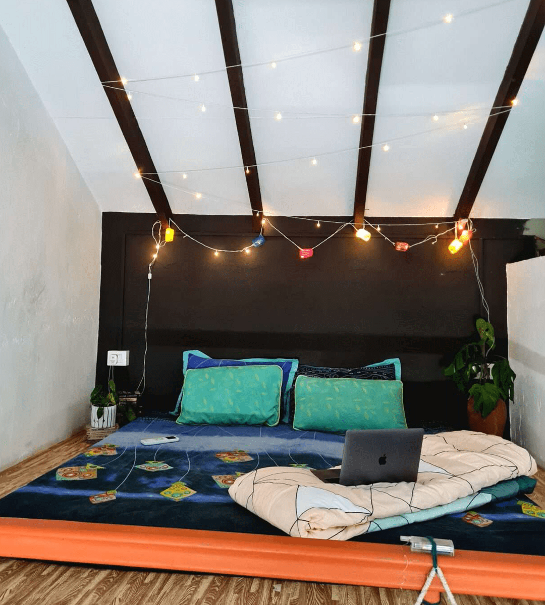 Cozy loft bed in the Loft Room at Valentine Villa Goa, featuring a comfortable mattress, soft linens, and a unique elevated view of the room's creative space under rustic wooden beams.
